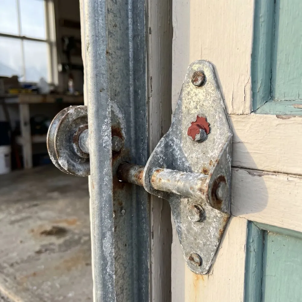 A garage door pulley and hinge bracket showing white salt bloom and rust freckling
