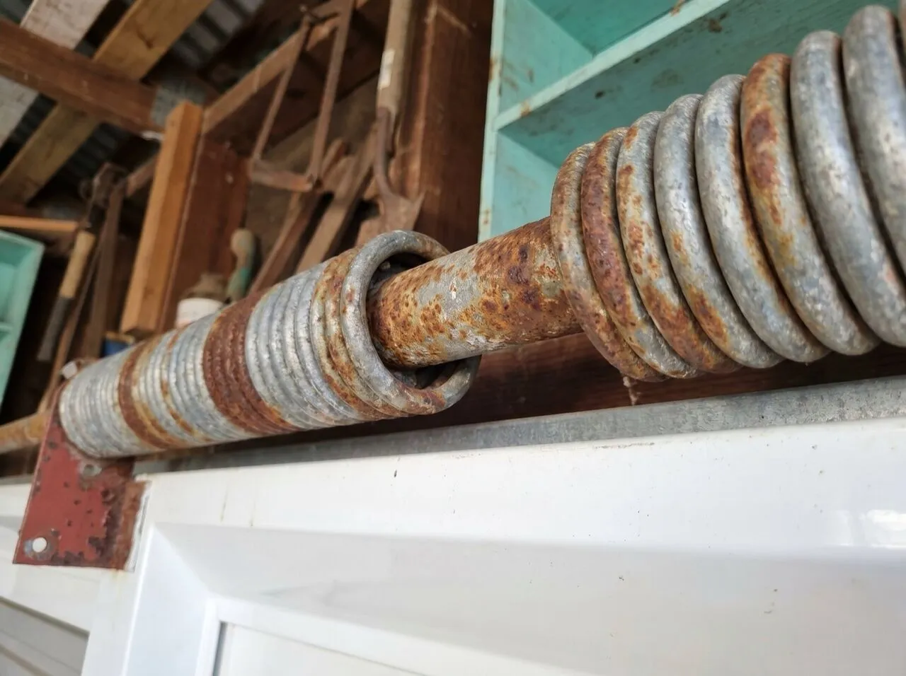 A corroded garage door torsion spring showing rust pitting on the coil